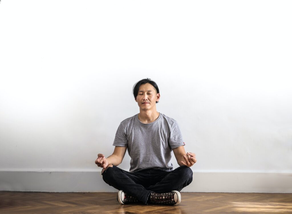 zen meditatiePhoto of Man in Gray T-shirt and Black Jeans on Sitting on Wooden Floor Meditating