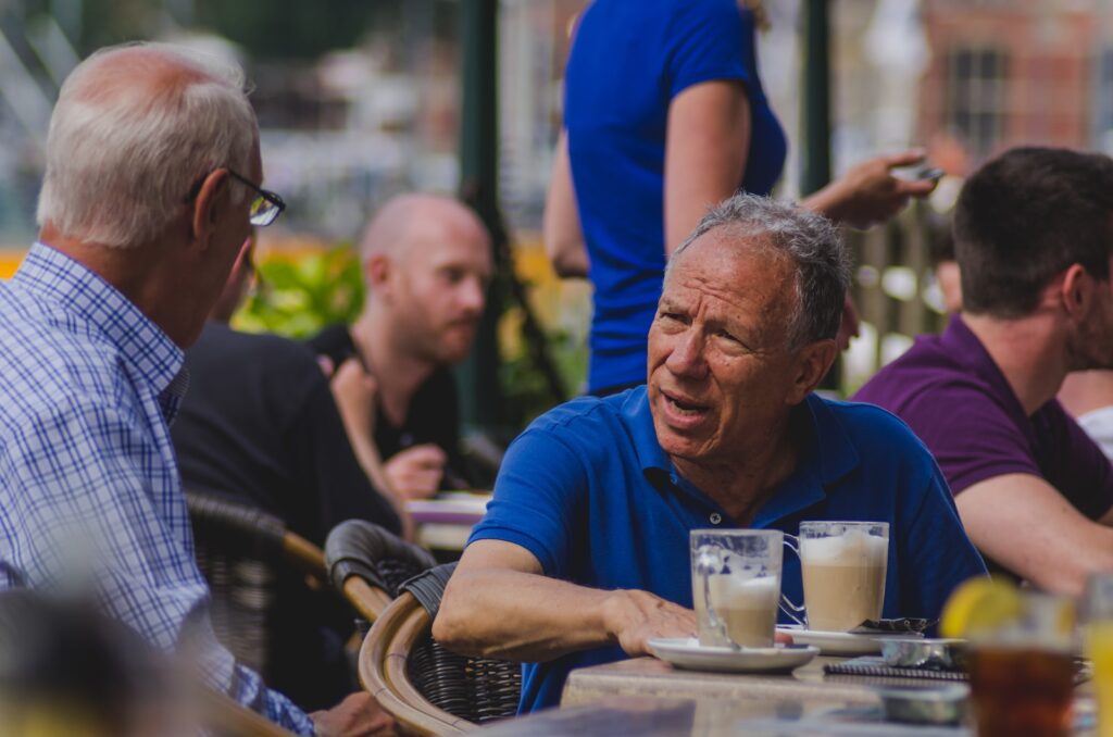 mindfulness man in blue polo shirt talking to man while drinking coffee