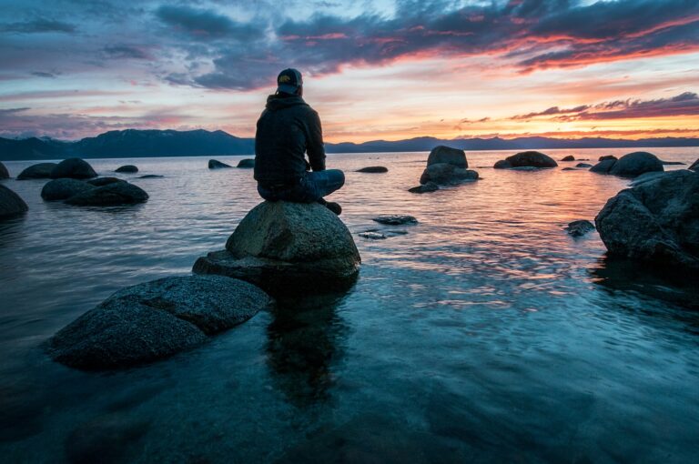 transedente meditatie man sitting on rock surrounded by water